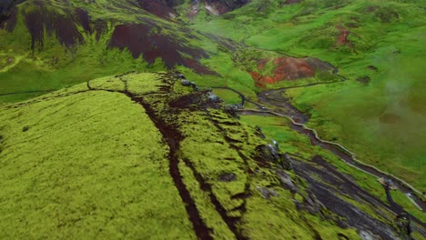 green moss covered terrain and steam from geothermal river in reykjadalur valley in iceland