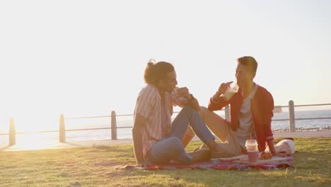 happy diverse gay male couple having picnic at promenade by the sea, slow motion