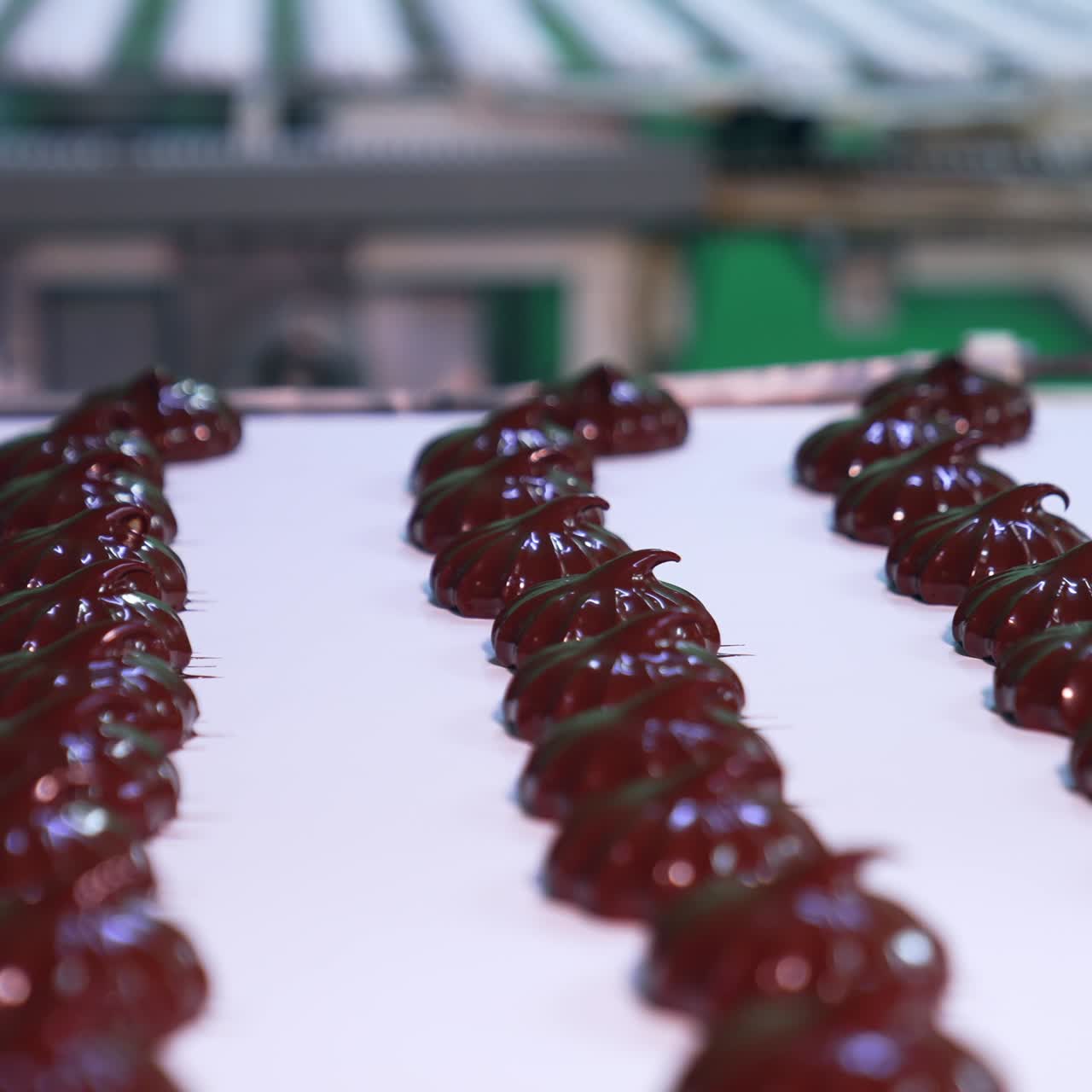 Two conveyor belts with marshmallows on the food factory. One conveyor with white zephyrs and another with coated in chocolate