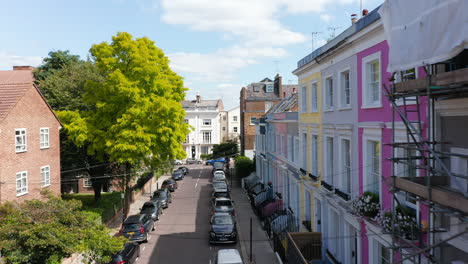 Forwards-fly-above-street-with-parked-cars-in-urban-neighbourhood.-Rising-reveal-of-cityscape.-London,-UK