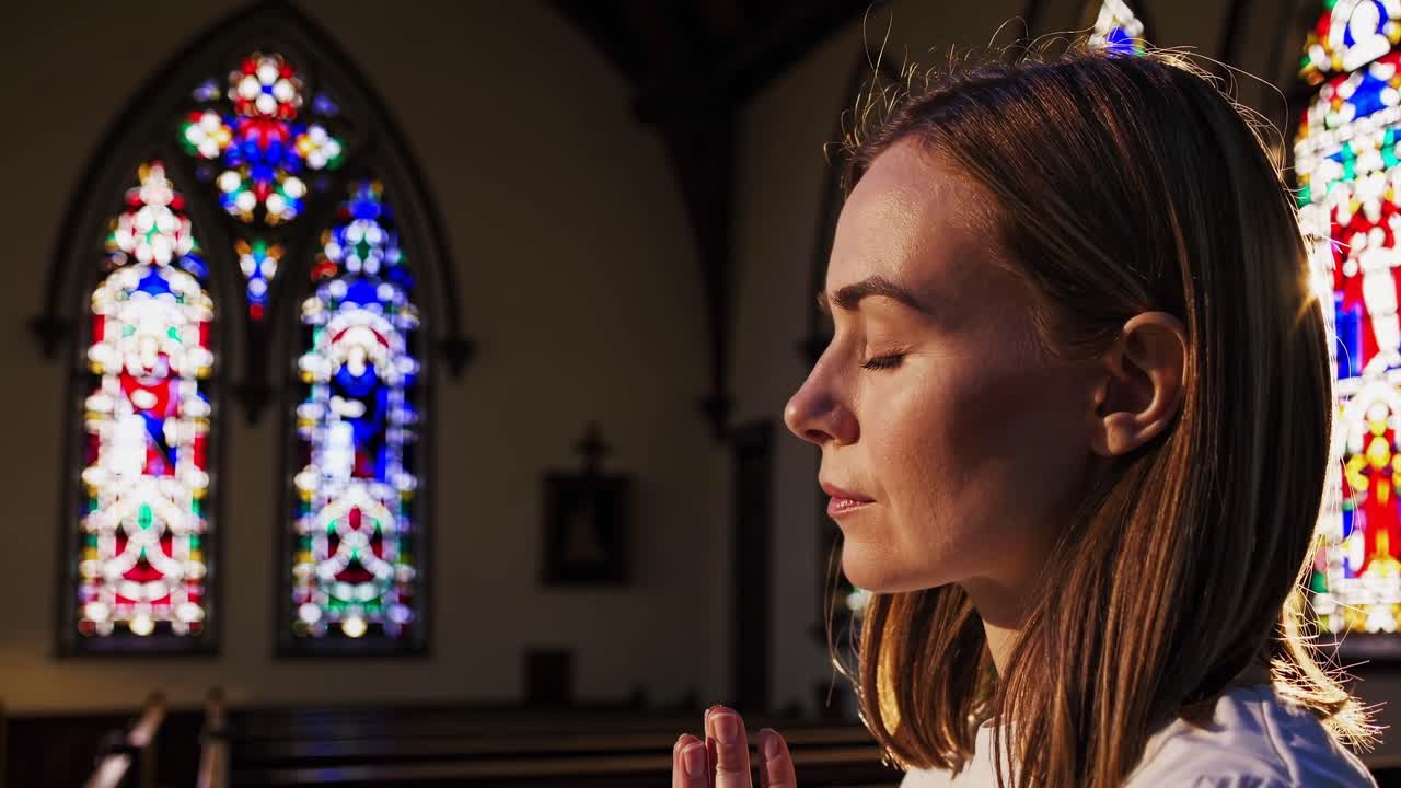 En rolig videoscene med en kvinde, der beder i en kirke, fanget i en sideprofil med sollys