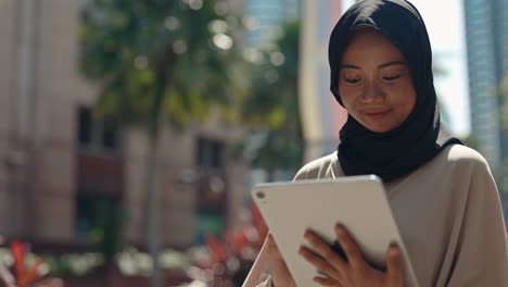 woman in hijab browsing tablet in urban setting