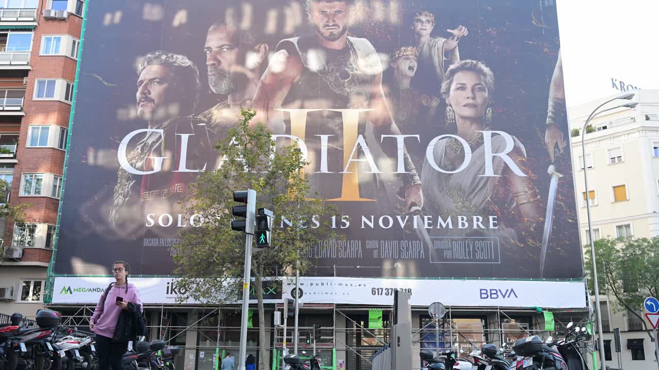 In the streets of Madrid, Spain, a large billboard advertises the movie Gladiator II (Gladiator 2), produced by Red Wagon Entertainment, distributed by Paramount Pictures, directed by Ridley Scott.