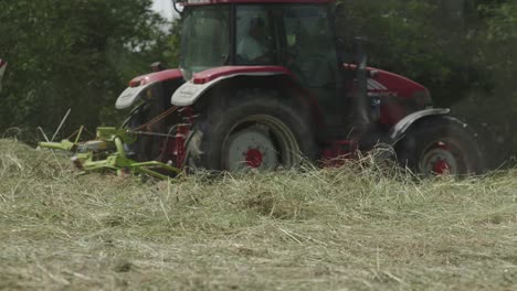 agricultor que opera un tractor sobre los campos con rastrillos rotativos