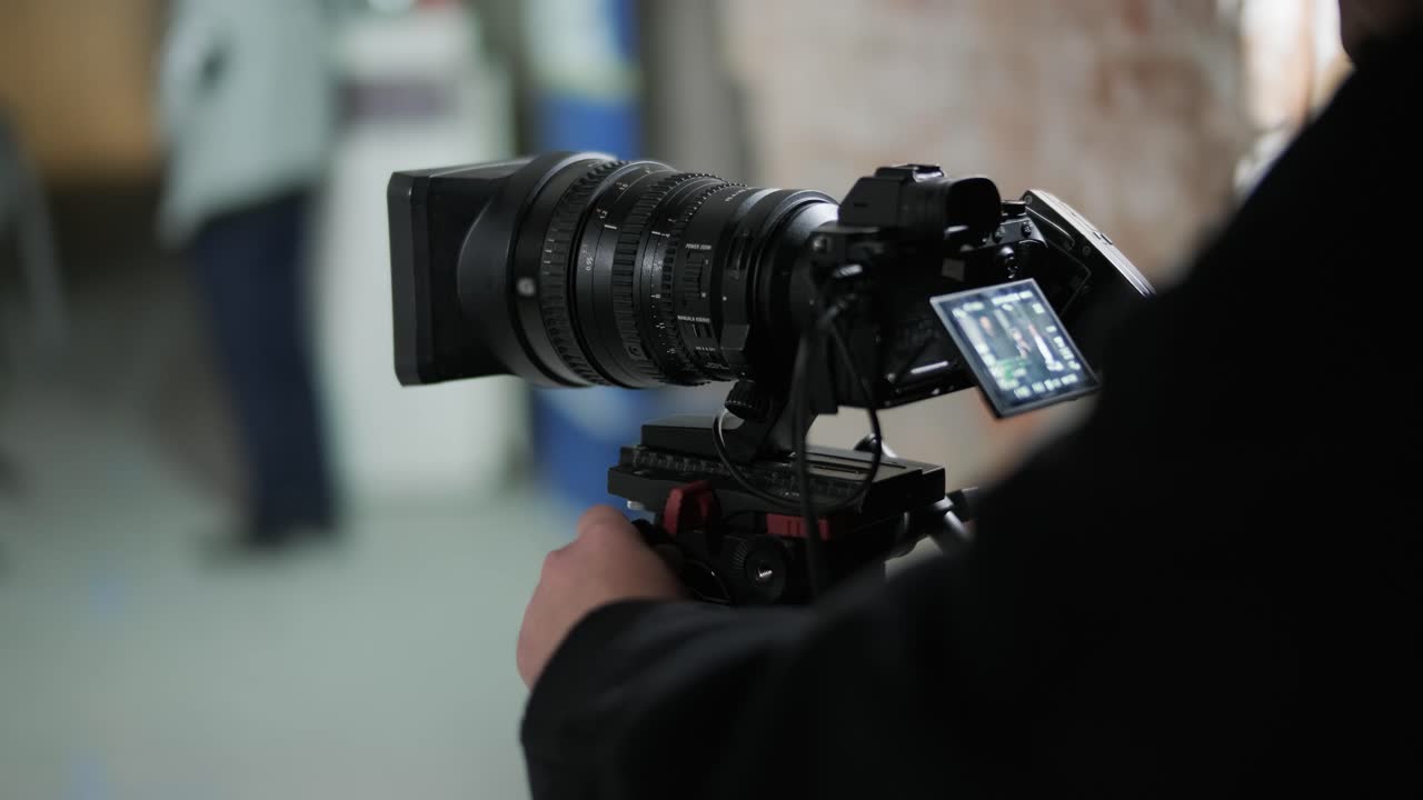 Uomo vestito di nero gira un video con una fotocamera e un obiettivo professionali