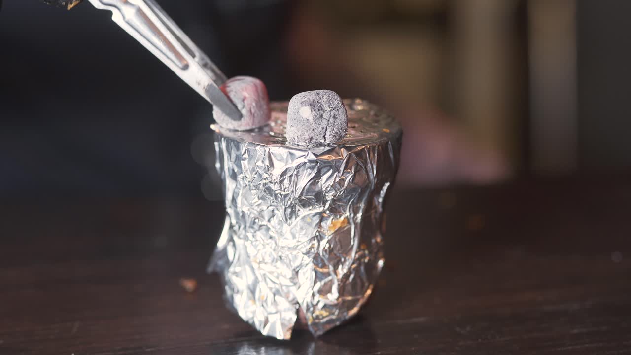 hombre poniendo carbón de narguile