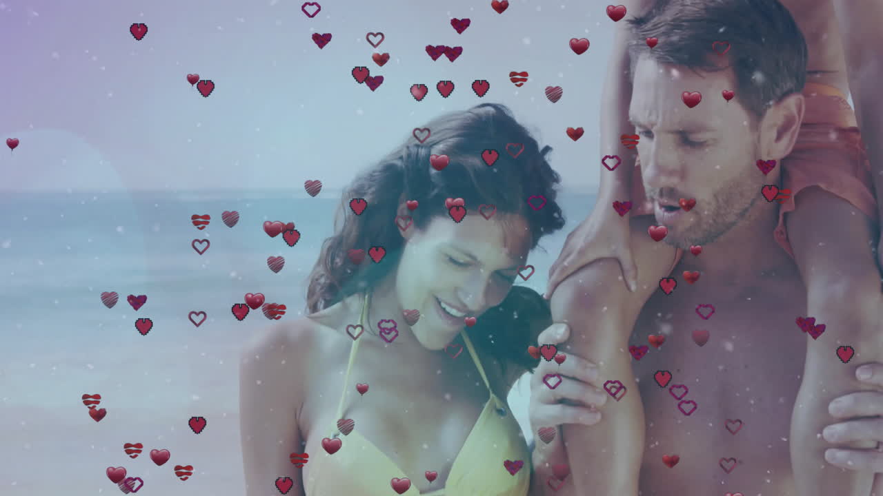 At beach, couple with floating heart animation overlaying their scene