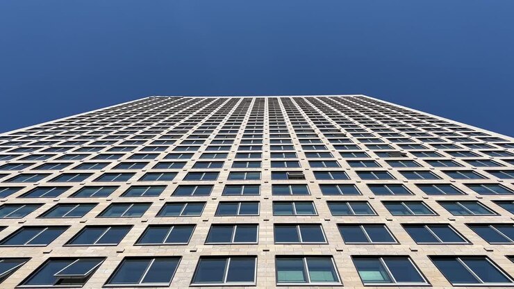Fachada de um arranha-céu moderno em Frankfurt, Alemanha, mostrando a grade repetitiva de janelas e a arquitetura contemporânea de um prédio de escritórios sob condições de luz do dia clara