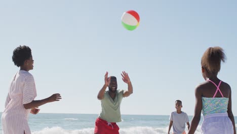 happy african american family playing ball, having fun on beach