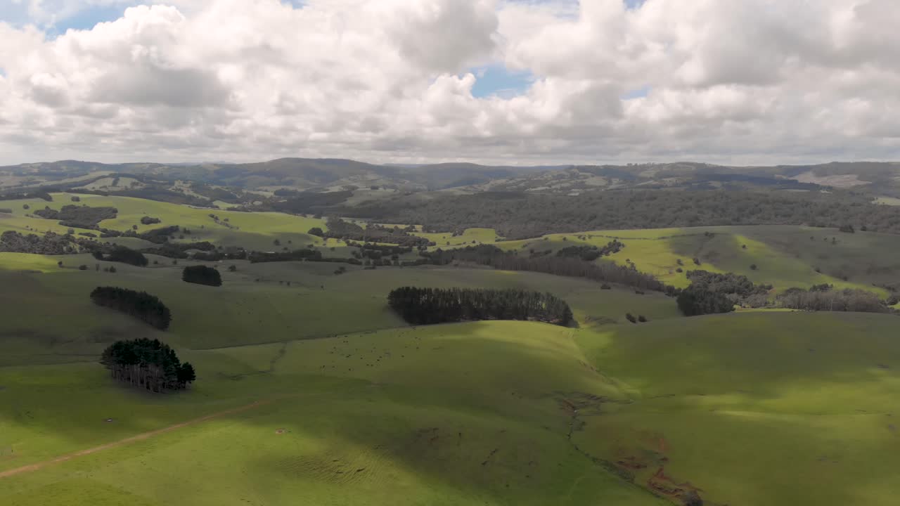 vuelo aéreo lento sobre un hermoso paisaje verde con colinas y montañas, bajo un cielo nublado