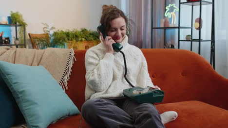 Woman-making-retro-telephone-from-90s-conversation-with-friends-sitting-call-on-sofa-at-home-in-room