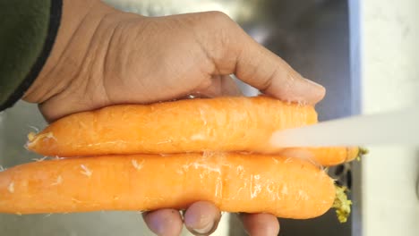 hand washing a carrot under running water