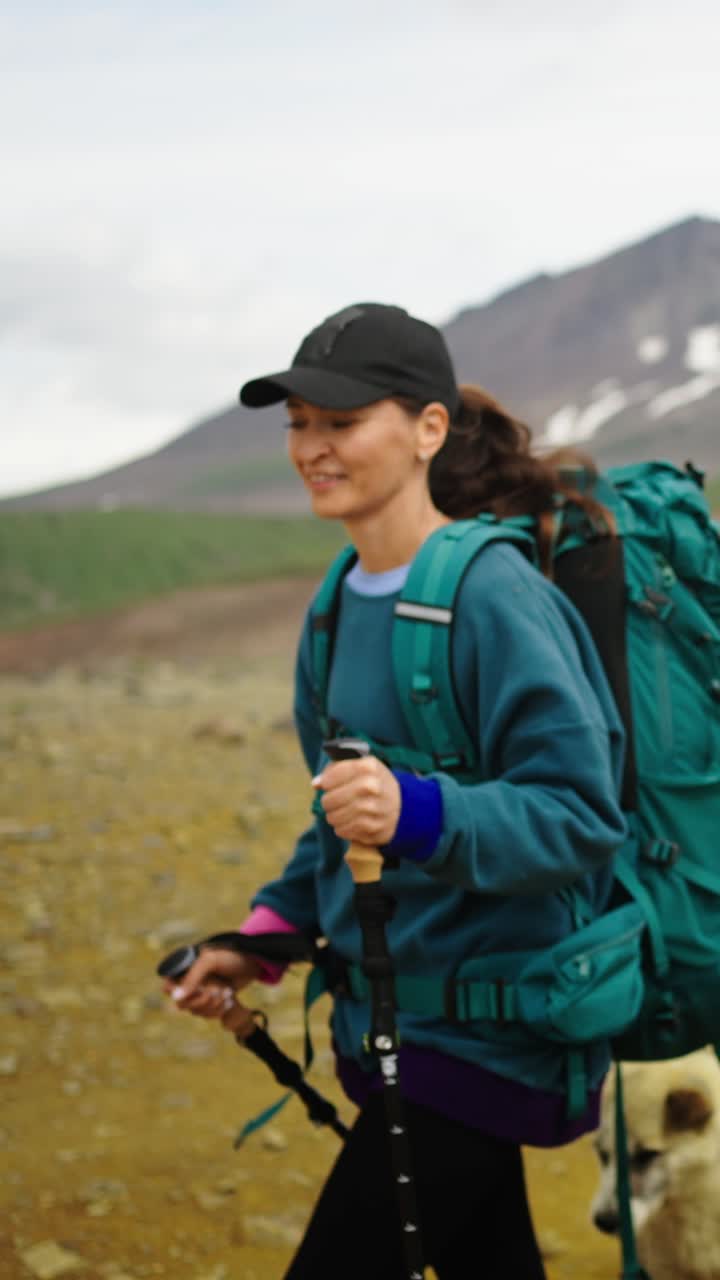 Donna che fa escursioni con zaino e bastoncini da trekking in un paesaggio montano