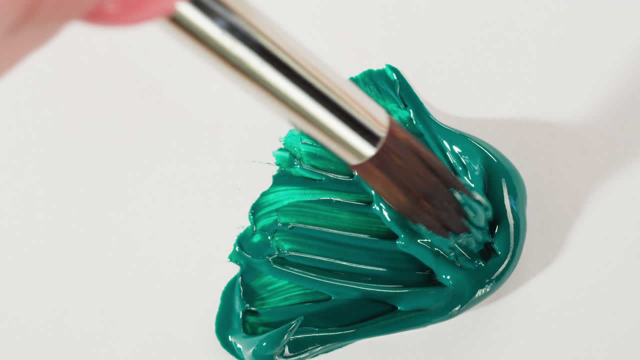 Pennello che stende pittura verde su una superficie bianca