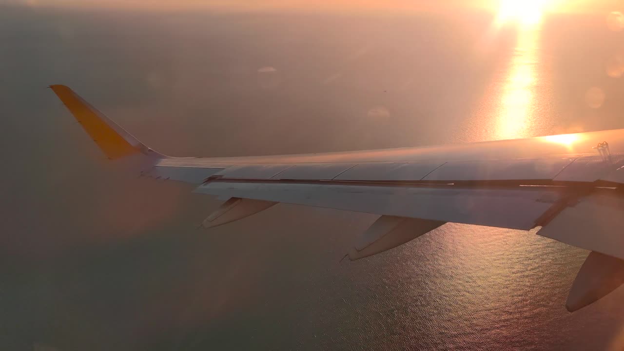 비행기가 바다 위로 기동하는 동안 일몰에 비행기 날개의 백라이트