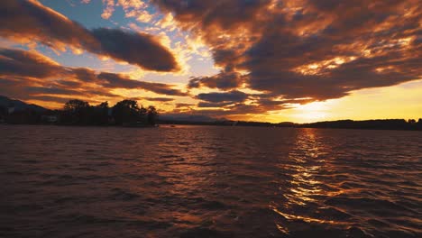 Boat-ride-on-the-historic-steam-ship-Ludwig-Fessler,-built-in-1927,-across-the-Chiemsee-lake-in-Bavaria,-home-to-King-Ludwig-II-of-Bavaria's-Versaille-replica-castle-on-an-island-by-sunset