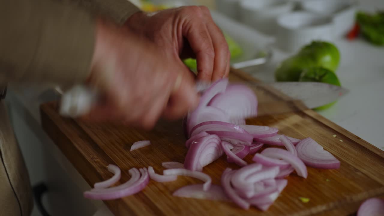 Professional chef cutting onions in kitchen.