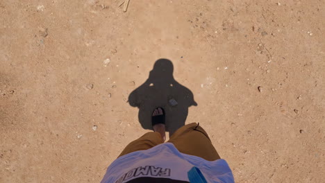 capturing a first-person perspective in slow motion whilst walking with shadows, filming feet and legs