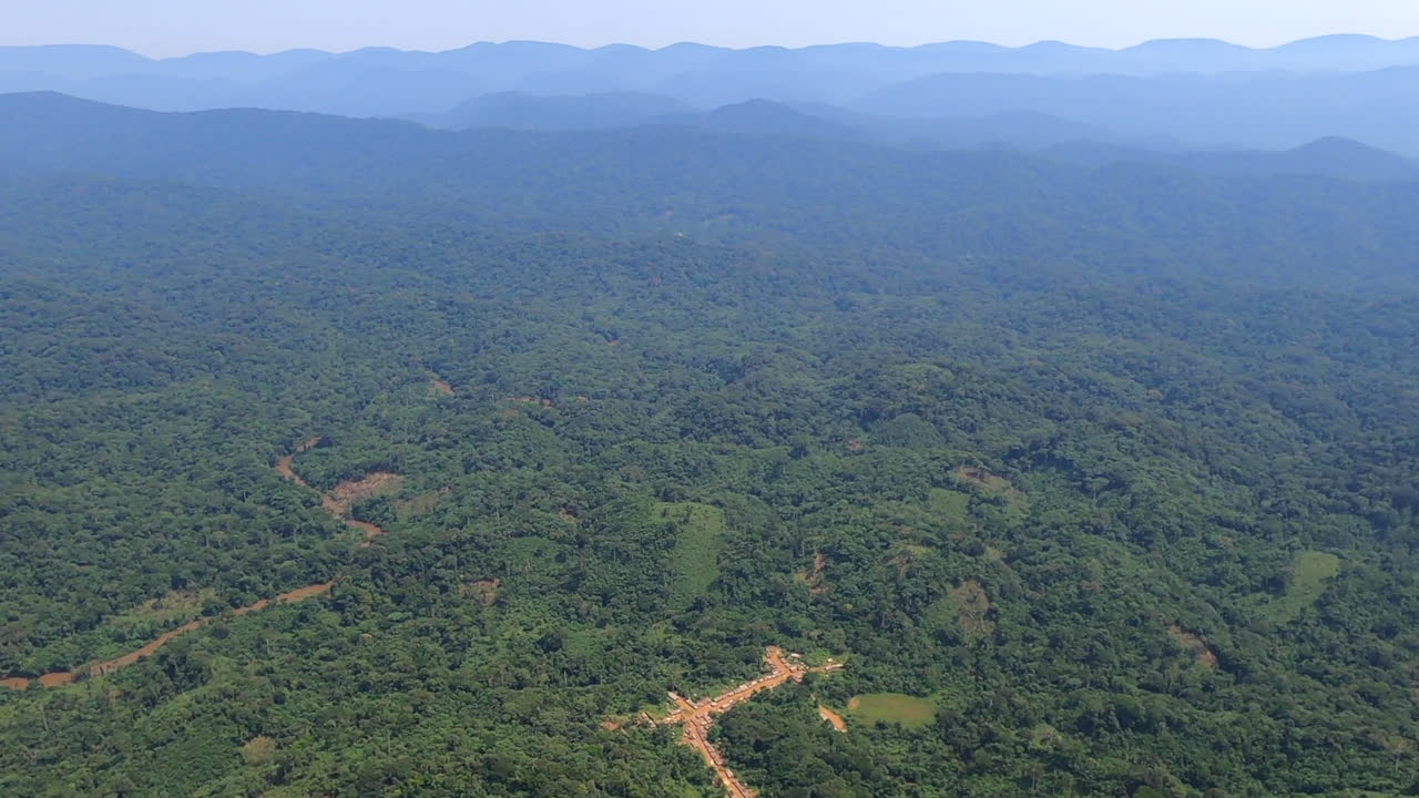 vuelo aéreo sobre un pequeño pueblo cerca de un río fangoso en la jungla de la rdc congo