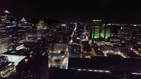 looking down on a traffic road surrounded by city buildings at night aerial, montreal