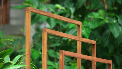 an outdoor wooden rack towel with swaying green leafage at background