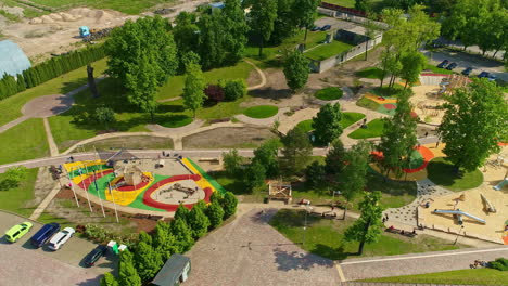 aerial drone shot flying high over kids playing in a recently constructed kids city park at daytime