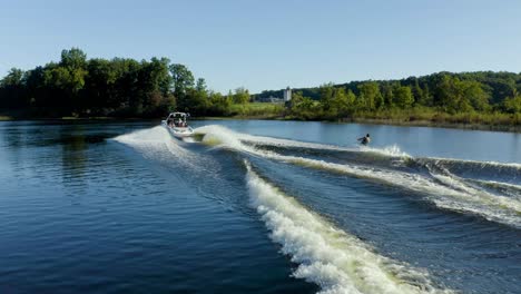 drone video of a wakeboarder behind a boat on a lake