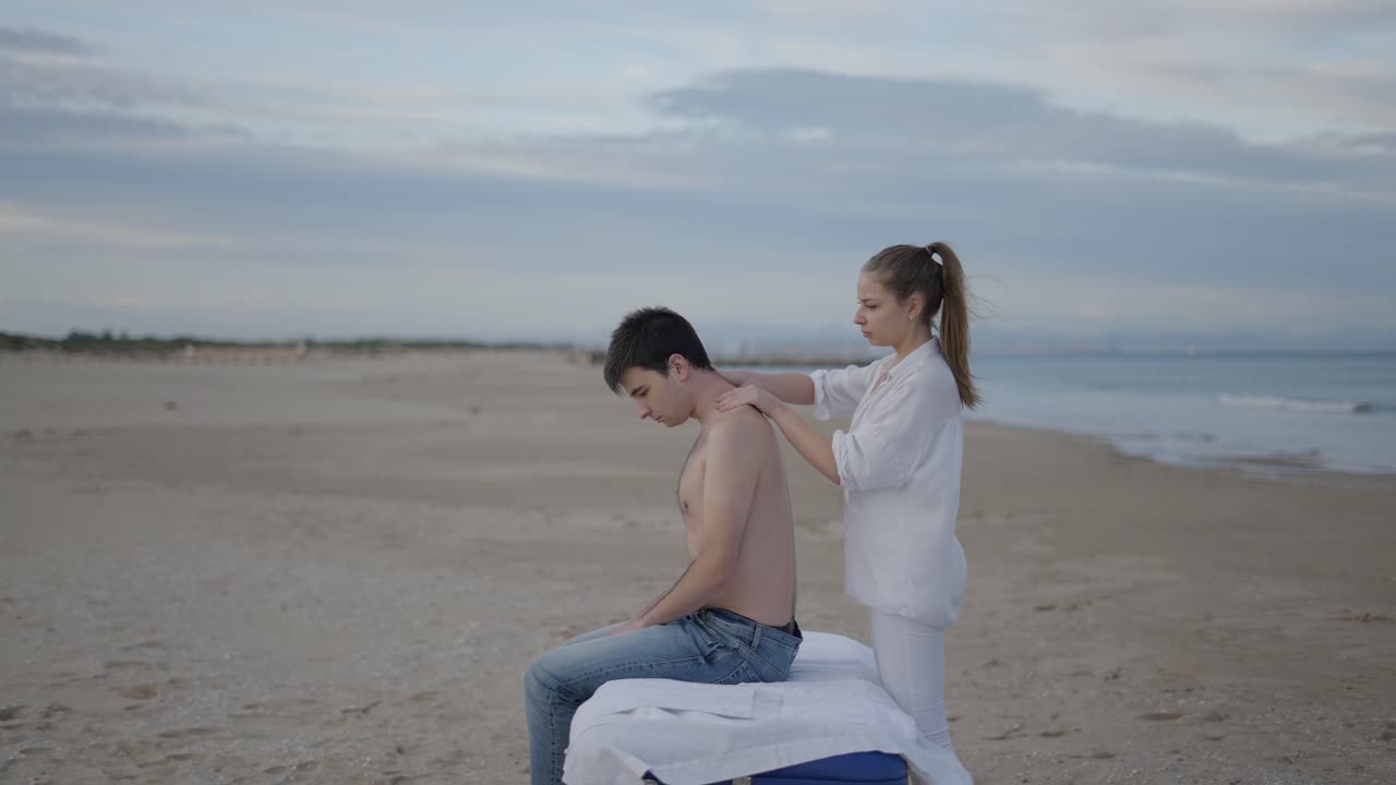Woman giving shoulder massage to man on the beach