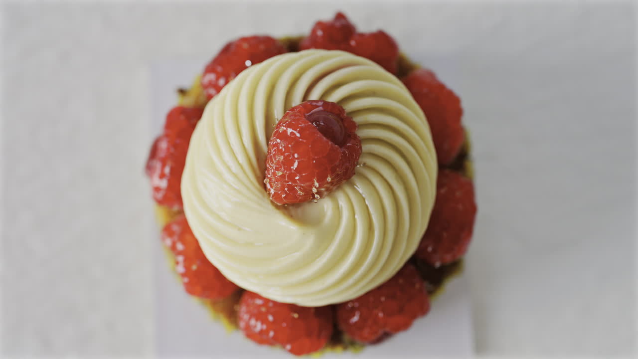Close up of a pistachio raspberry tartlet on a white plate