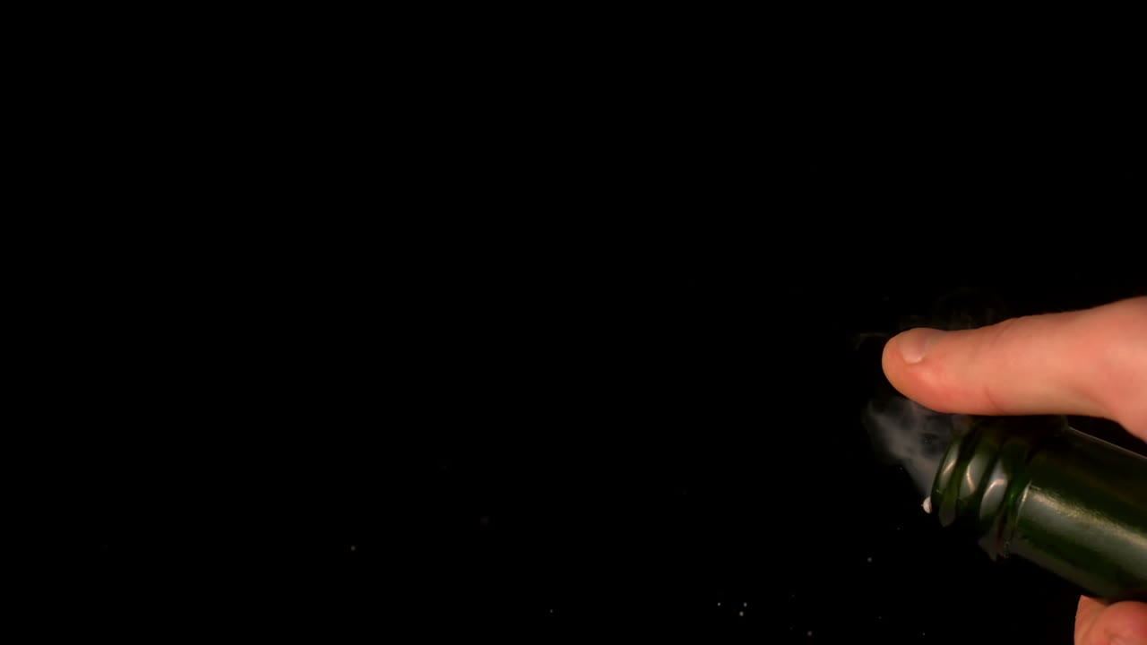 Hand popping champagne cork on black background