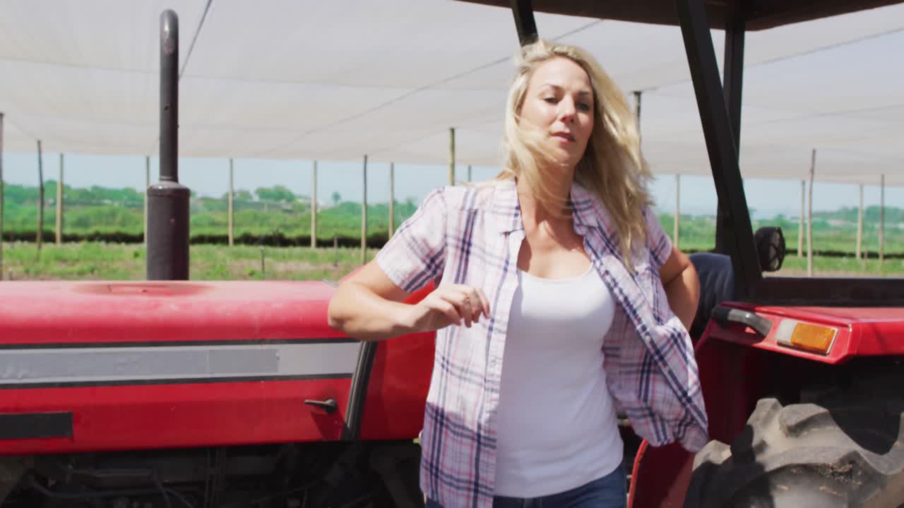 video de una mujer caucásica feliz de pie frente a un tractor