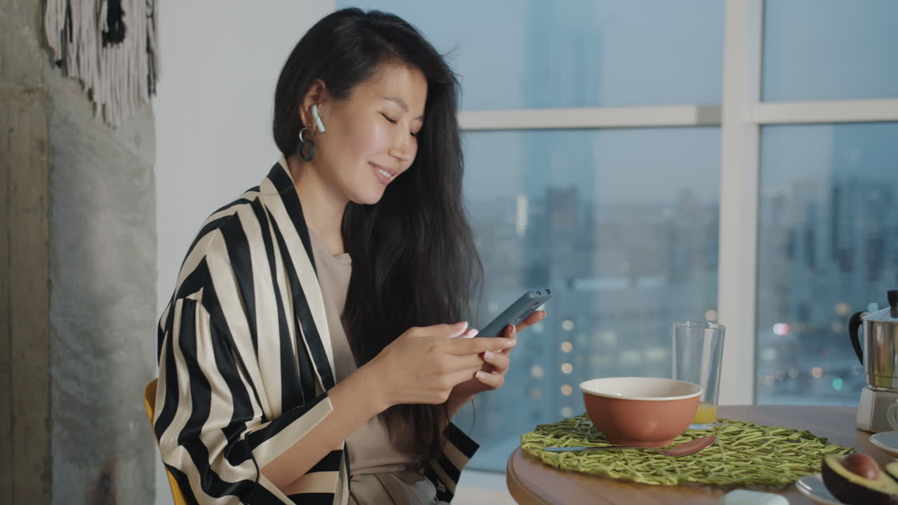 Woman using phone during breakfast with city view
