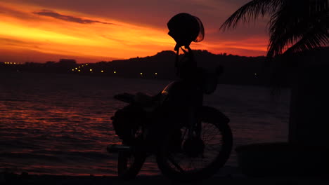 stunning colourful sunset on tropical coastline beach, with illuminated village at distance, asia vibes static shot