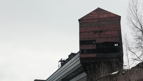 large, bricked, and weathered industrial structure towering against a cloudy sky