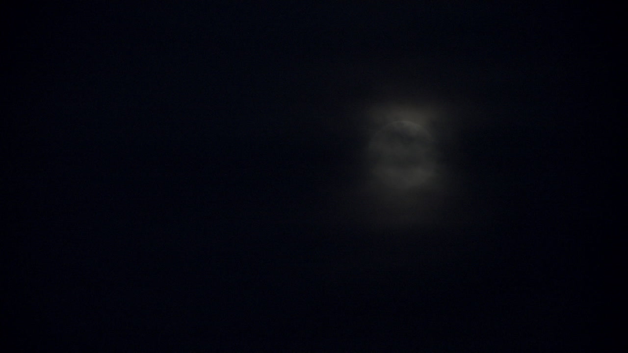 밤하늘의 보름달 앞을 지나가는 검은 구름