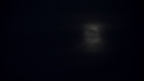 nubes negras pasando frente a una luna llena en el cielo nocturno