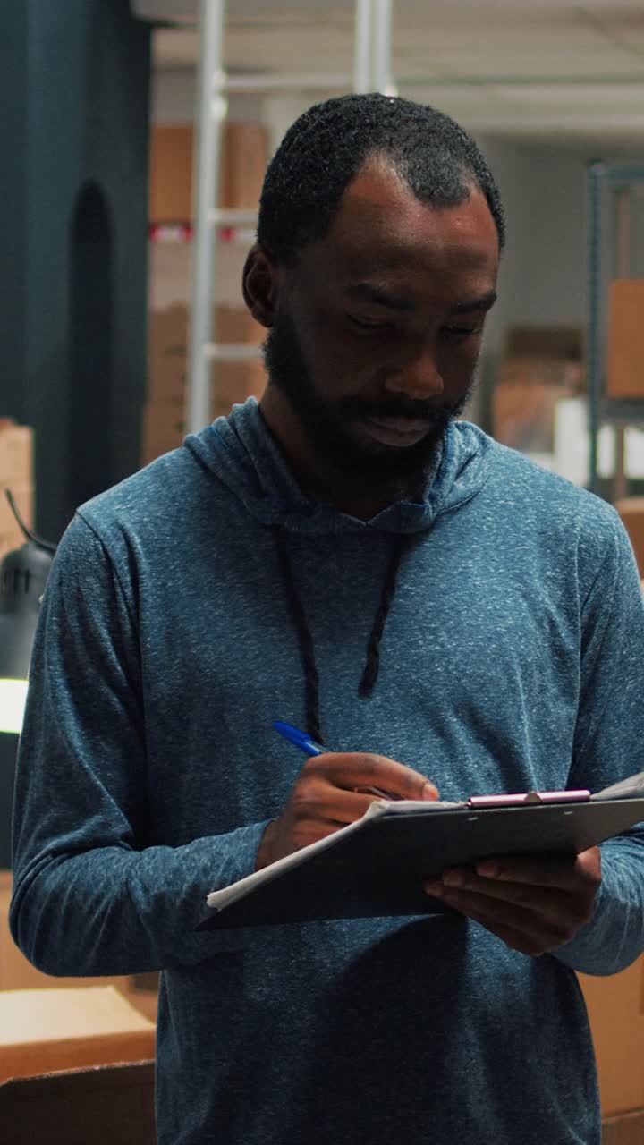 Vertikal video: Afroamerikansk medarbejder tager lagerbeholdningsnotater på udklipsholderpapirer