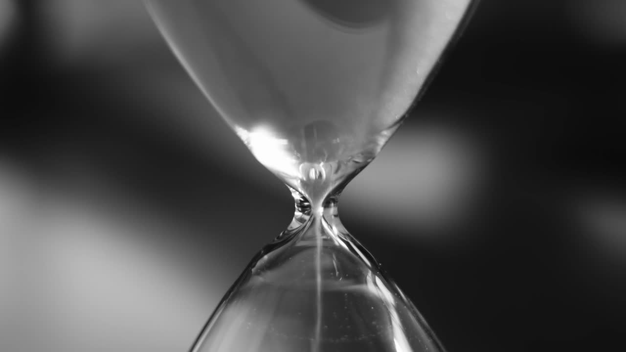 Hourglass with white sand pouring inside, eternal time, infinity, business time