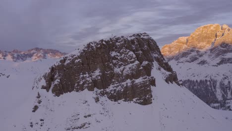 vuelo suave de drones alrededor de cumbres cubiertas de nieve de montañas iluminadas a la luz del sol al atardecer - dolomitas en italia