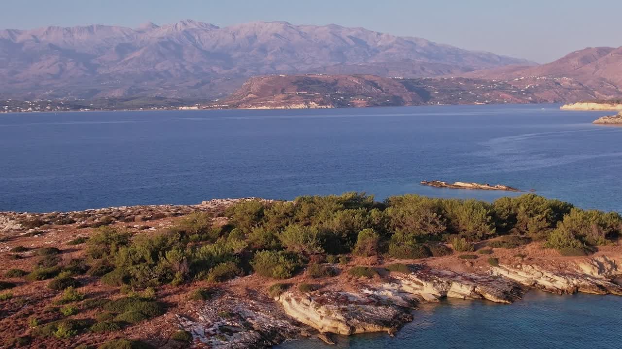 Vista aérea panorâmica de península rochosa e mar azul com montanhas