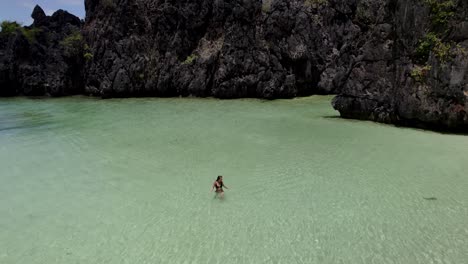 a person swims alone in crystal clear turquoise water near rocky cliffs on a sunny day