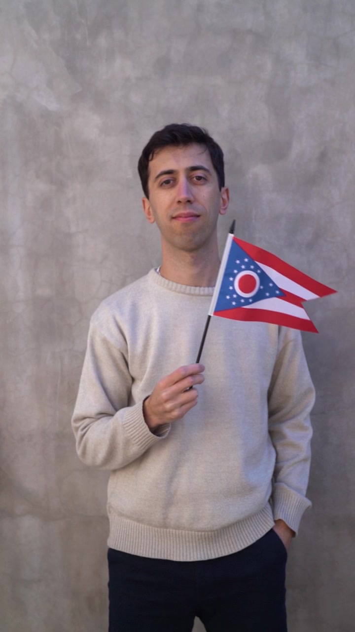Ripresa verticale di un giovane adulto maschio che sventola la bandiera dello stato dell'Ohio. Slow motion