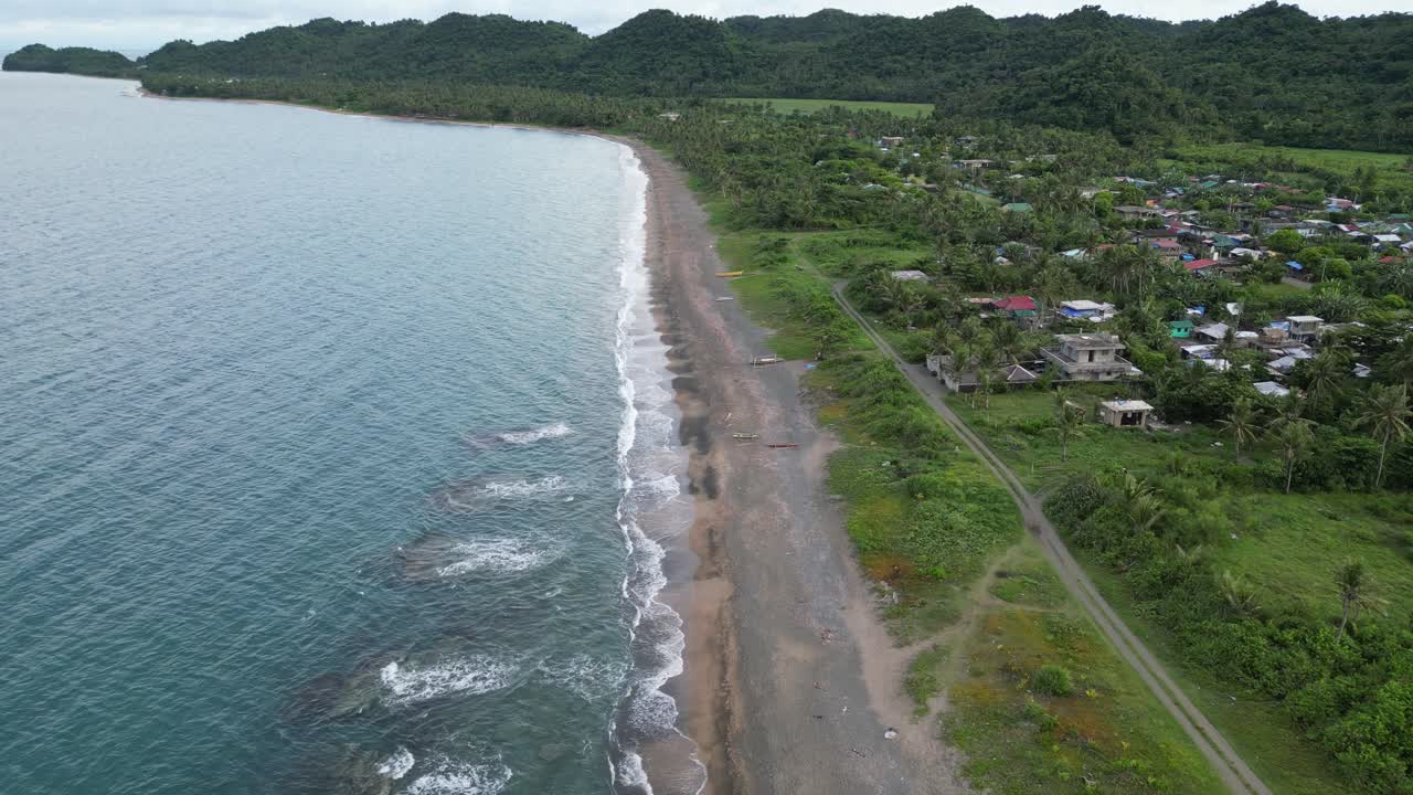 필리핀 카탄두아네스에 있는 기이하고 숲이 우거진 마을을 마주한 해안선에 부딪히는 청록색의 거친 파도의 멋진 공중 전망
