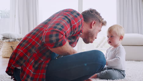 padre tocando el ukelele con el hijo pequeño en casa, vista lateral