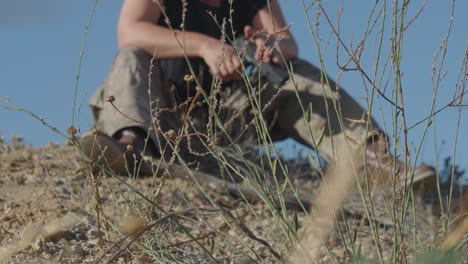 una mujer soldado rubia estadounidense sentada recargando una pistola en el campo de combate