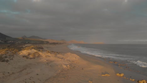 Avance-Aéreo-A-Lo-Largo-De-La-Playa-De-Calheta-Al-Atardecer-En-Un-Día-Nublado,-Portugal