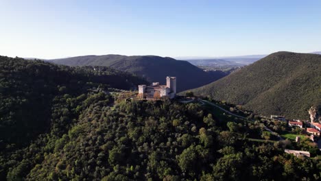 Vista-Aérea-De-Una-Fortaleza-De-Piedra-Medieval-En-La-Cima-De-Una-Colina-Verde-En-Narni,-Italia