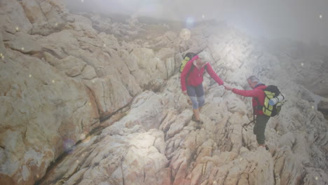 feliz pareja de ancianos caucásicos tomados de la mano caminando por las rocas, sobre los puntos de luz bokeh que caen