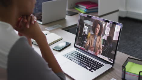 african american woman having a video conference on laptop with female office colleague at office