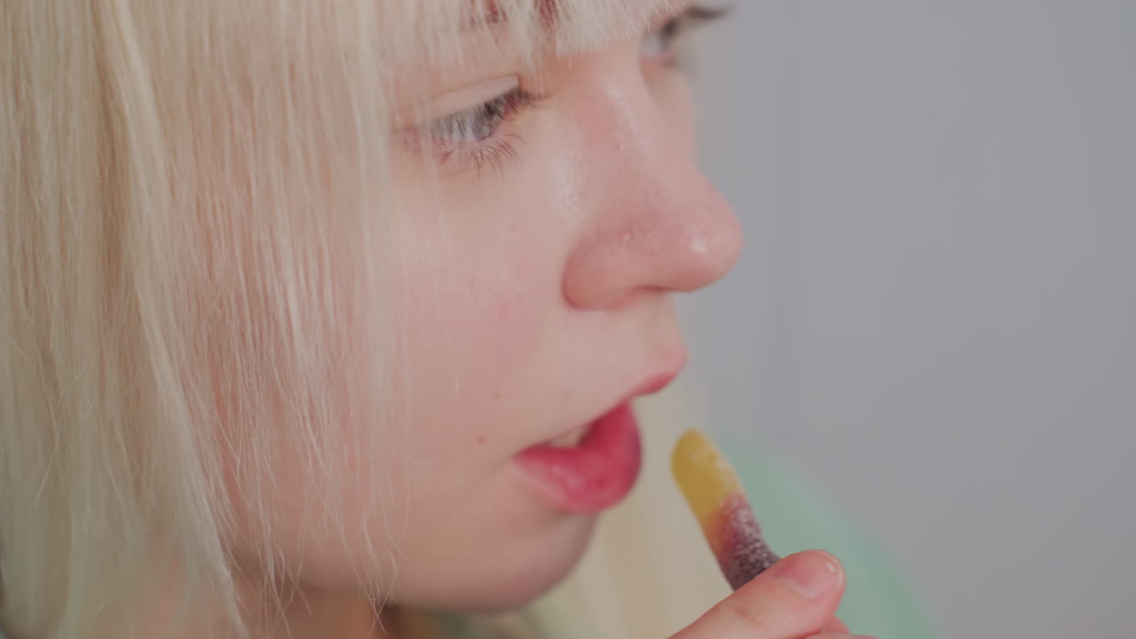 Extreme close up of young blonde woman drinking coffee from brown glass cup, her eyes are focused and calm, showcasing peaceful moment of morning routine in cozy indoor setting with soft lighting